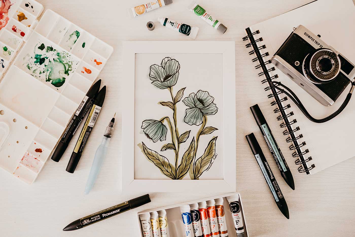 Artistic flat lay photograph featuring paints and a watercolour flower