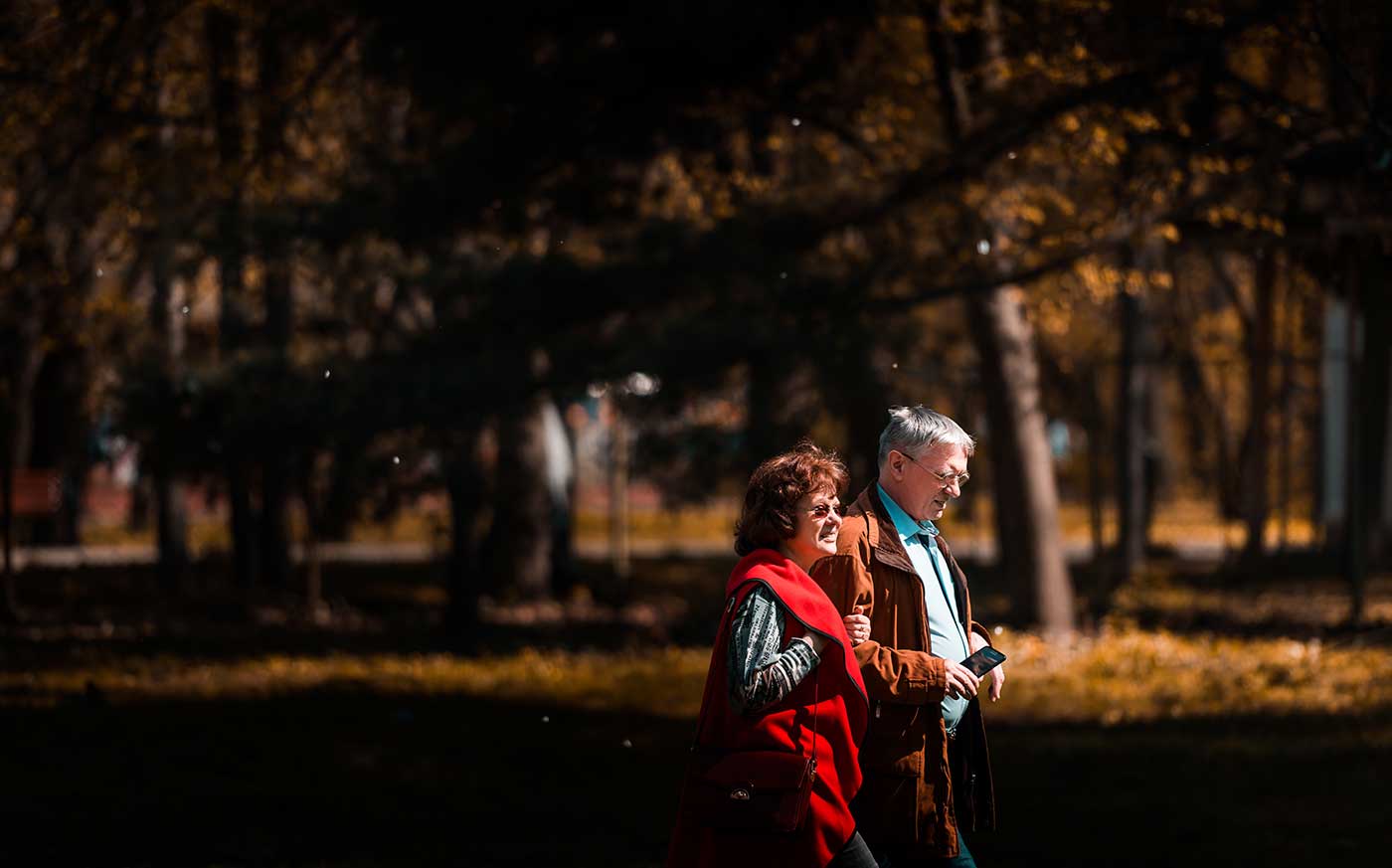 Over 50's dating: couple taking a walk in a park.