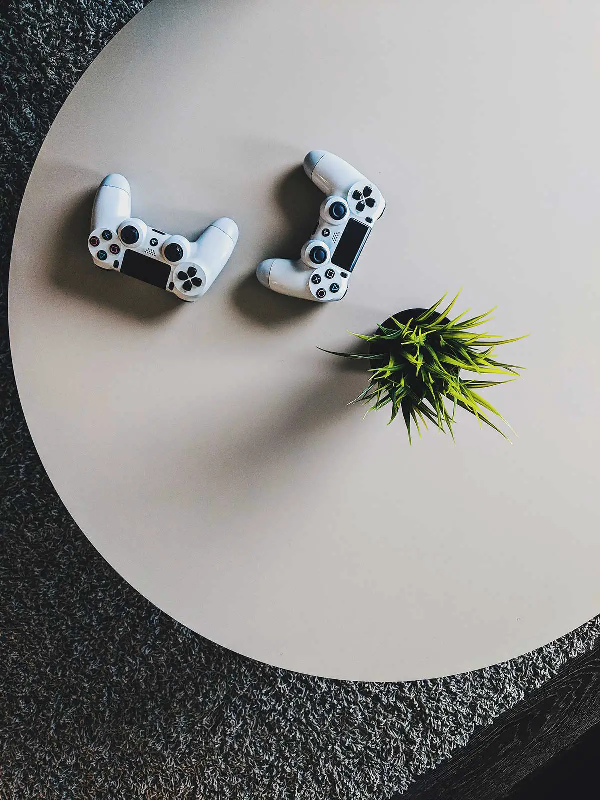 Two playstation controllers on a desk with a plant to show lockdown Date Ideas For Gamers.