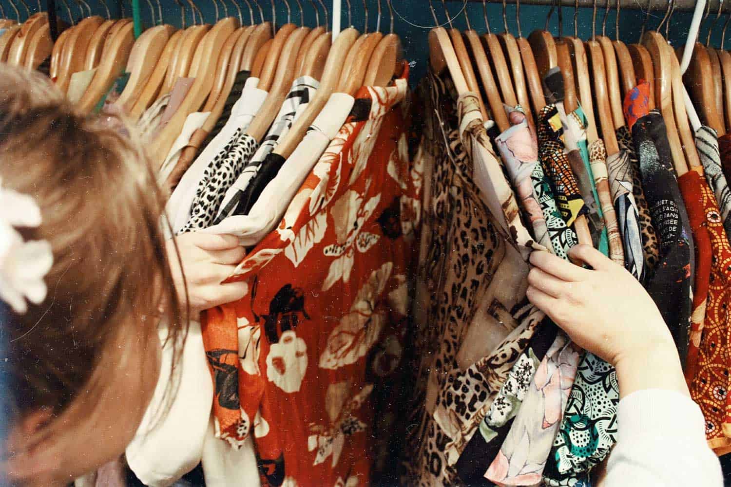 Girl searching through vintage clothes on a rail.