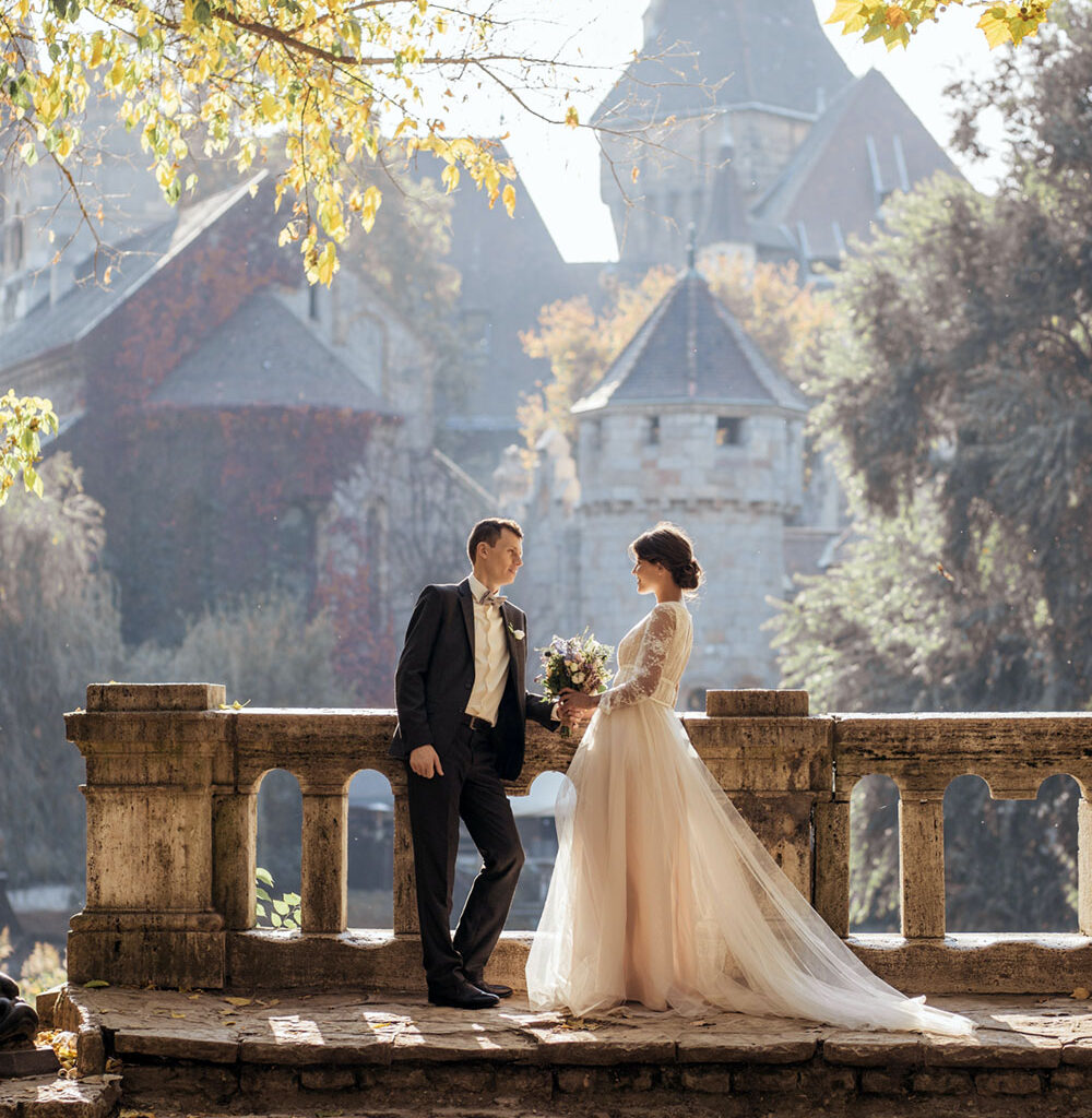 Wedding couple standing by castle.