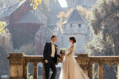 Wedding couple standing by castle.