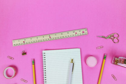 creative flatlay with assorted stationery and a bright pink background