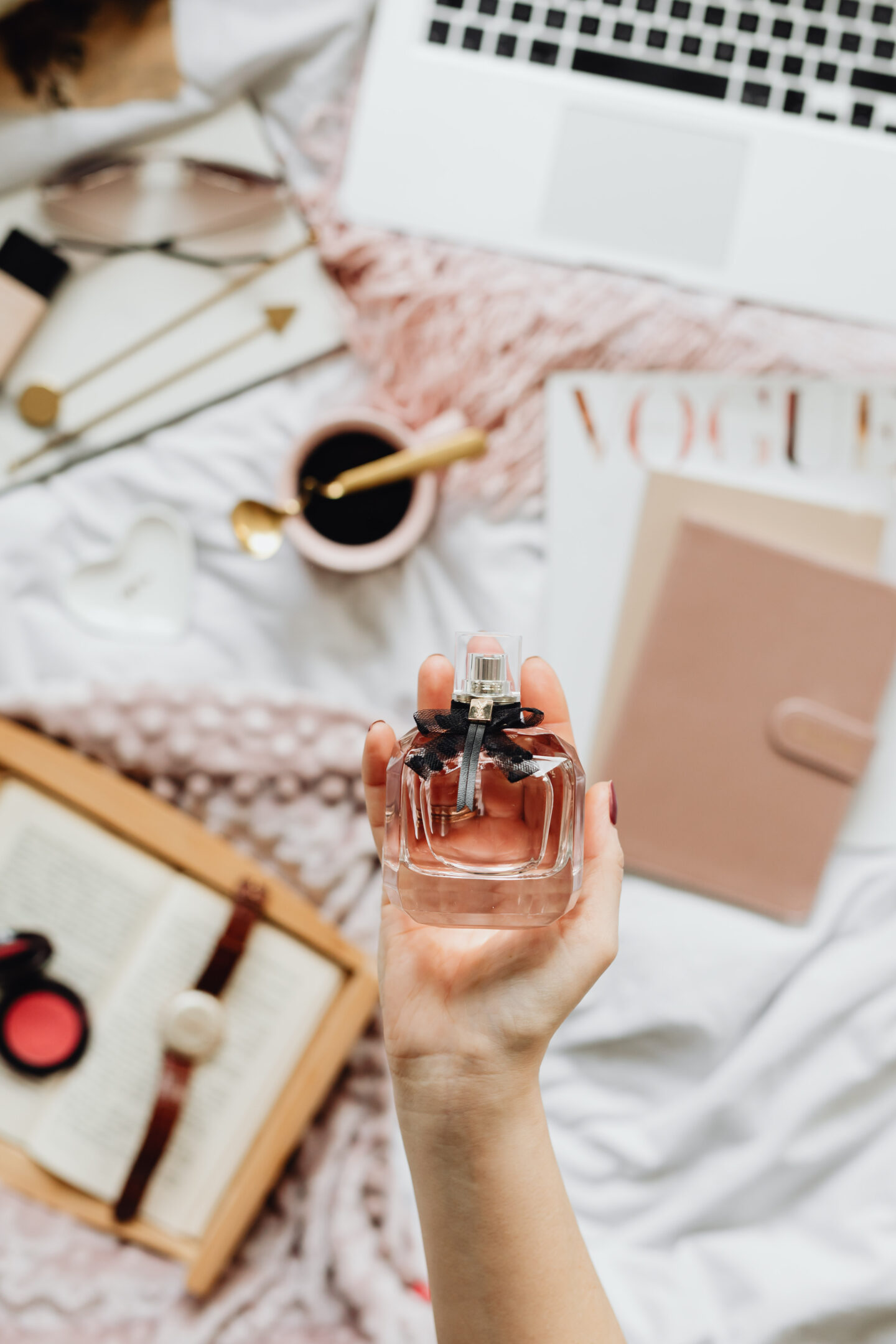 feminine flatlay featuring perfume, workspace, laptop, book