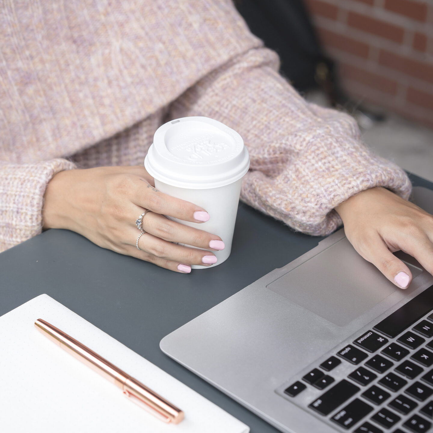 Female entrepreneur using macbook holding coffee cup.