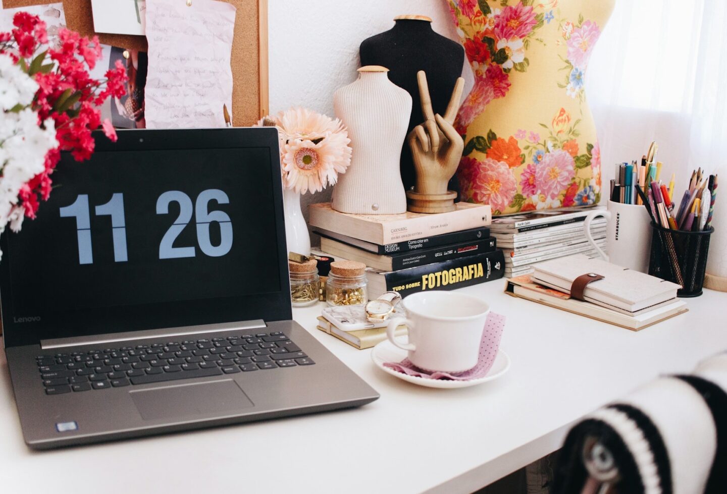 feminine creative workspace with art supplies, books and a laptop.