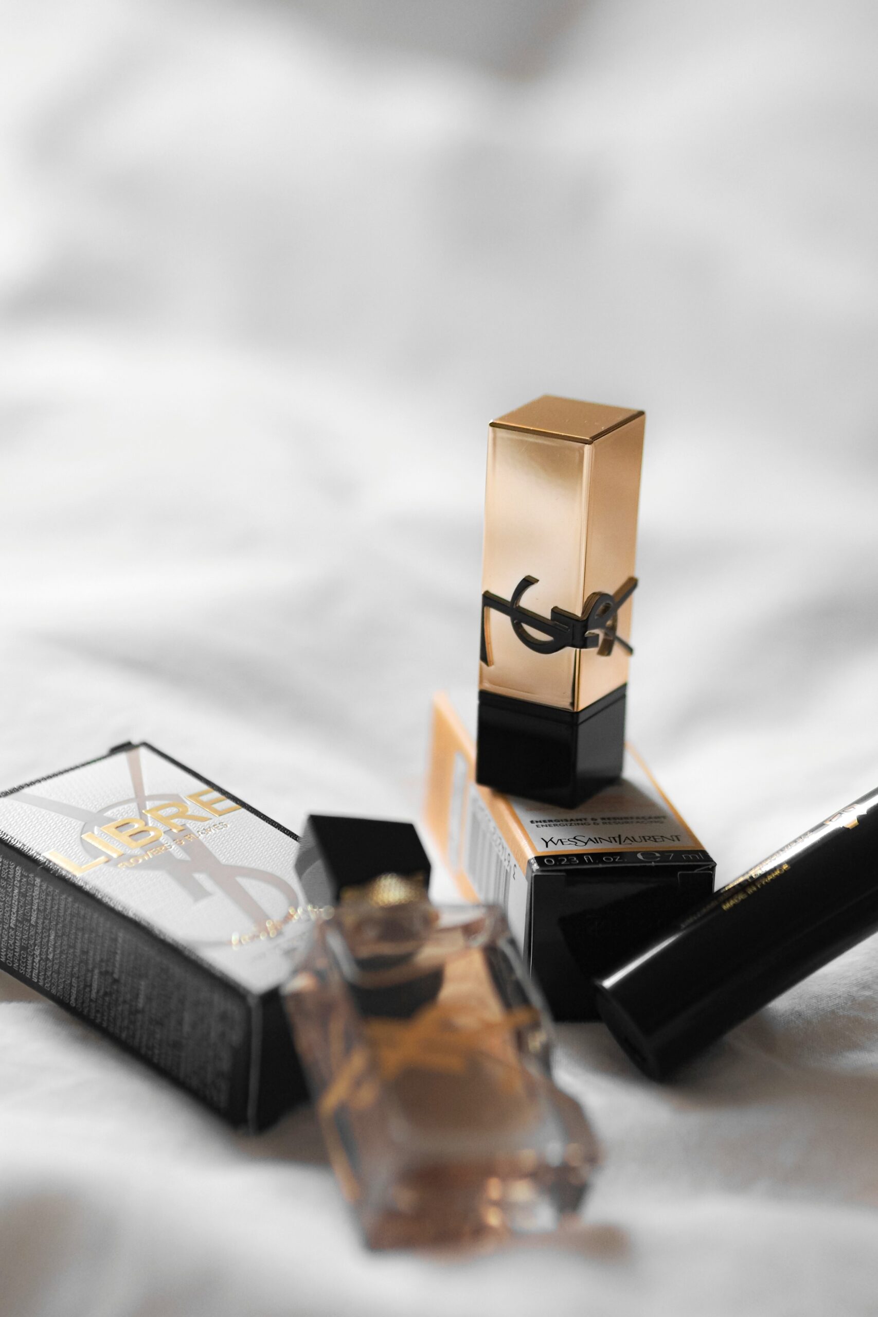 high-end expensive brand makeup and perfume on a bed.