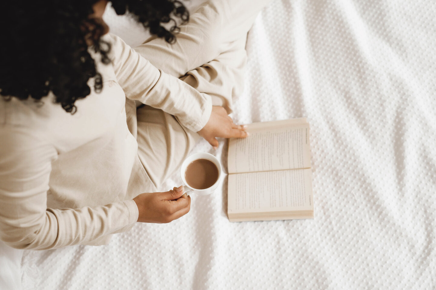 woman holding book and cup of tea.