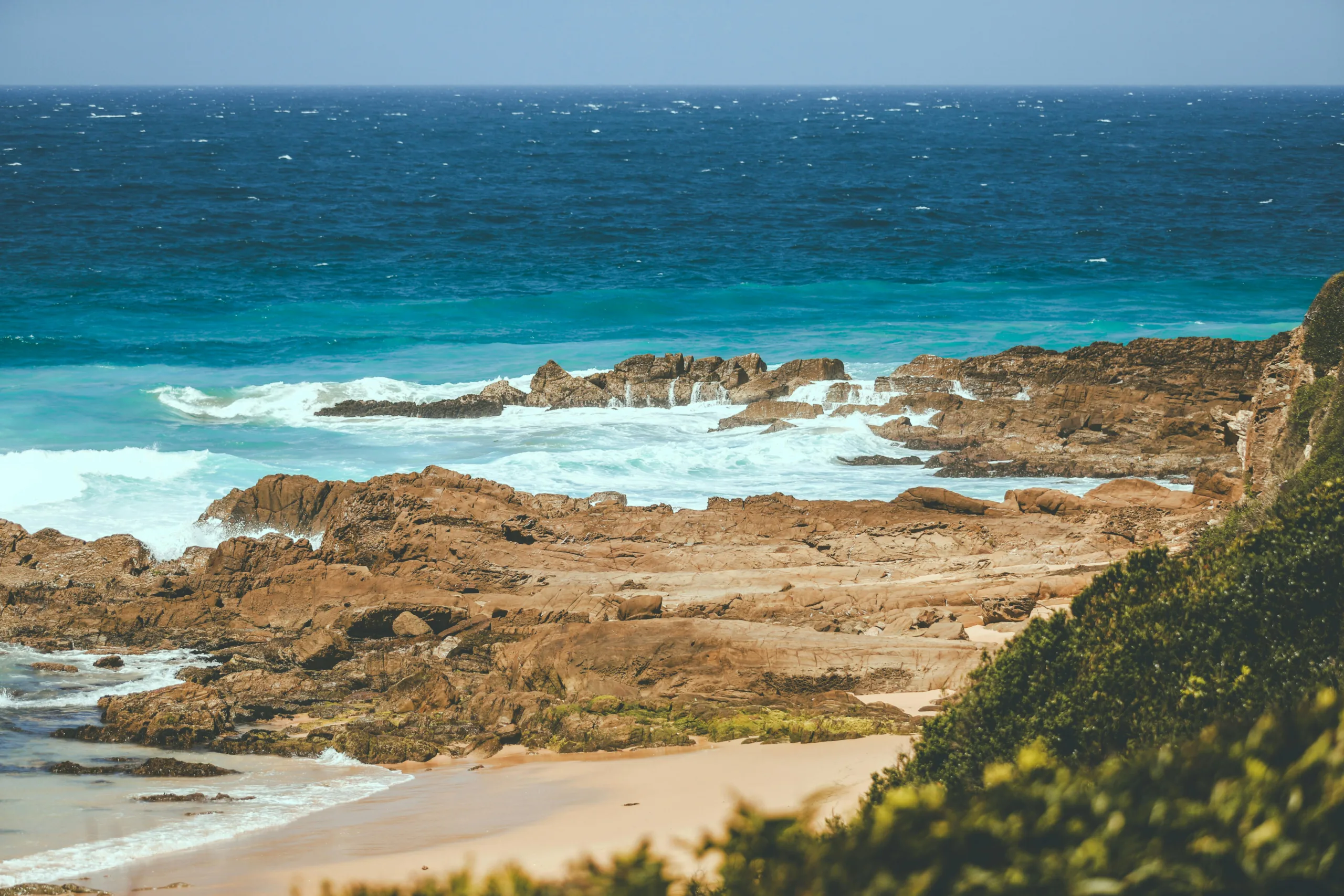Solo traveller journaling in a notebook beside the Australian coastline