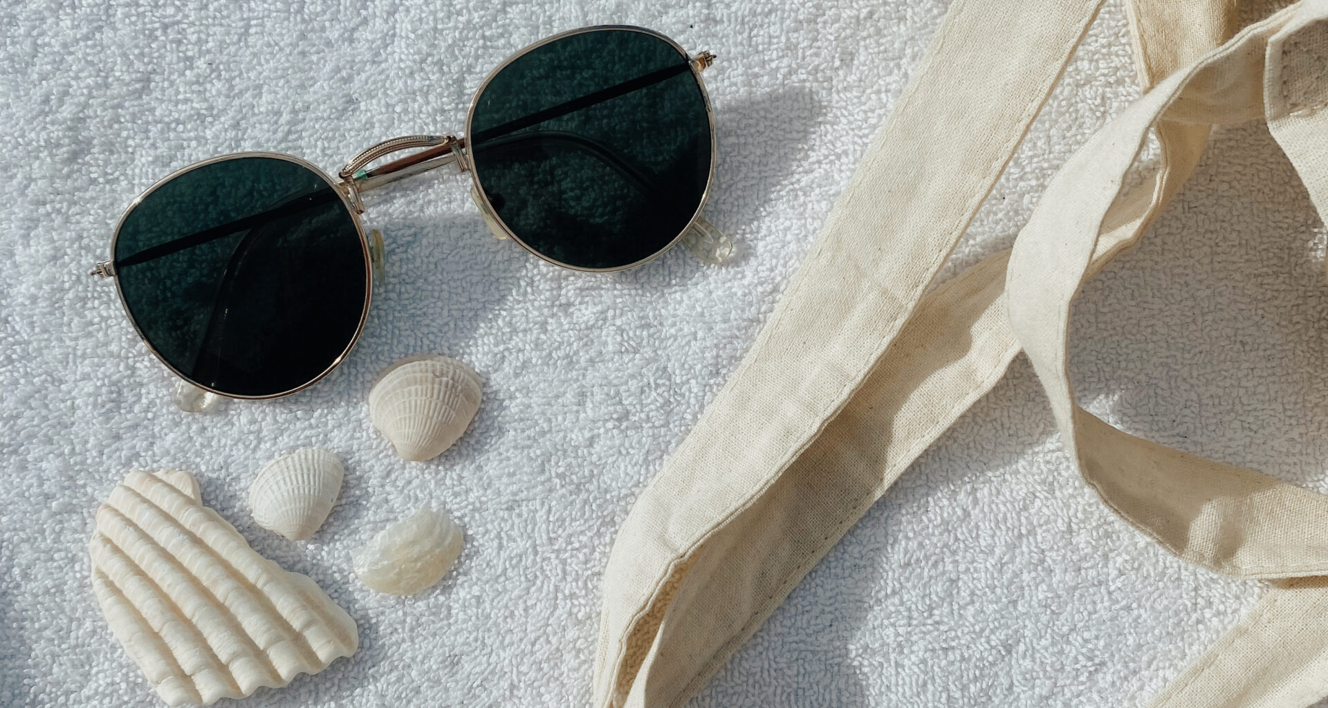 beach flatlay with sunglasses, seashells and tote