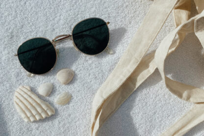 beach flatlay with sunglasses, seashells and tote