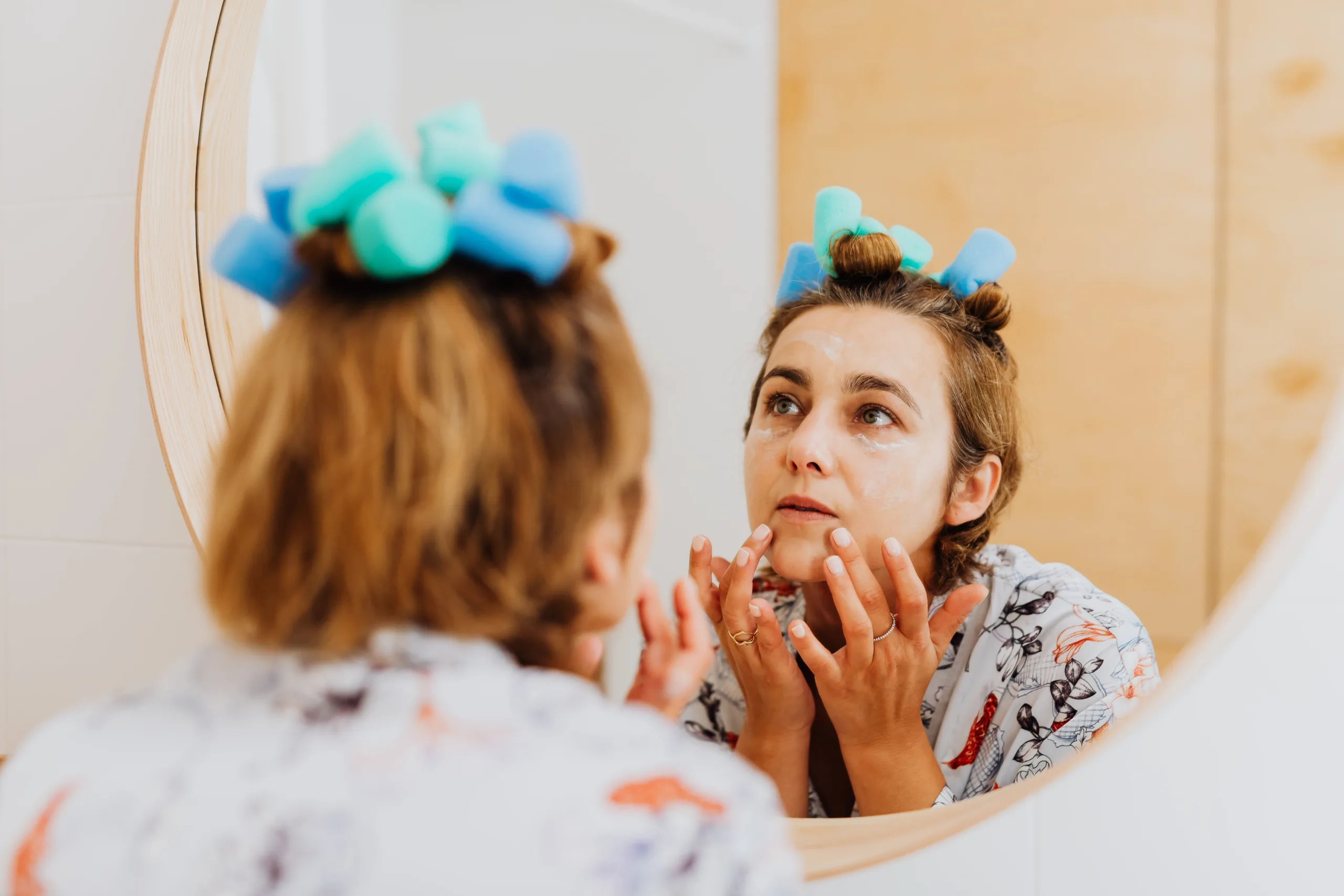 Woman looking at face doing skincare in mirror